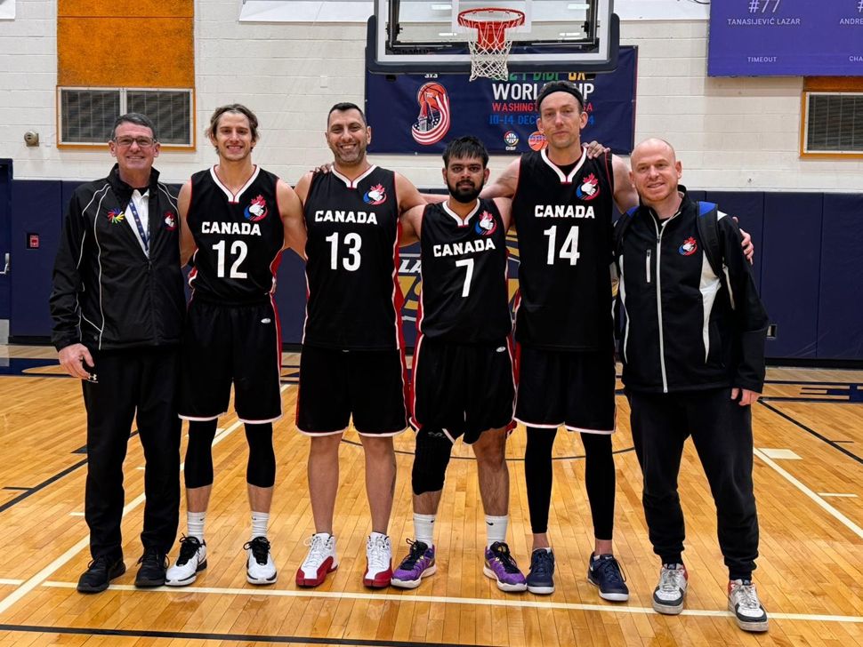 Six men standing side-by-side, four of them are wearing basketball jerseys.