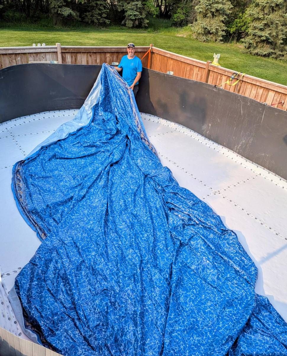 a man stretches a pool liner out over an above ground pool