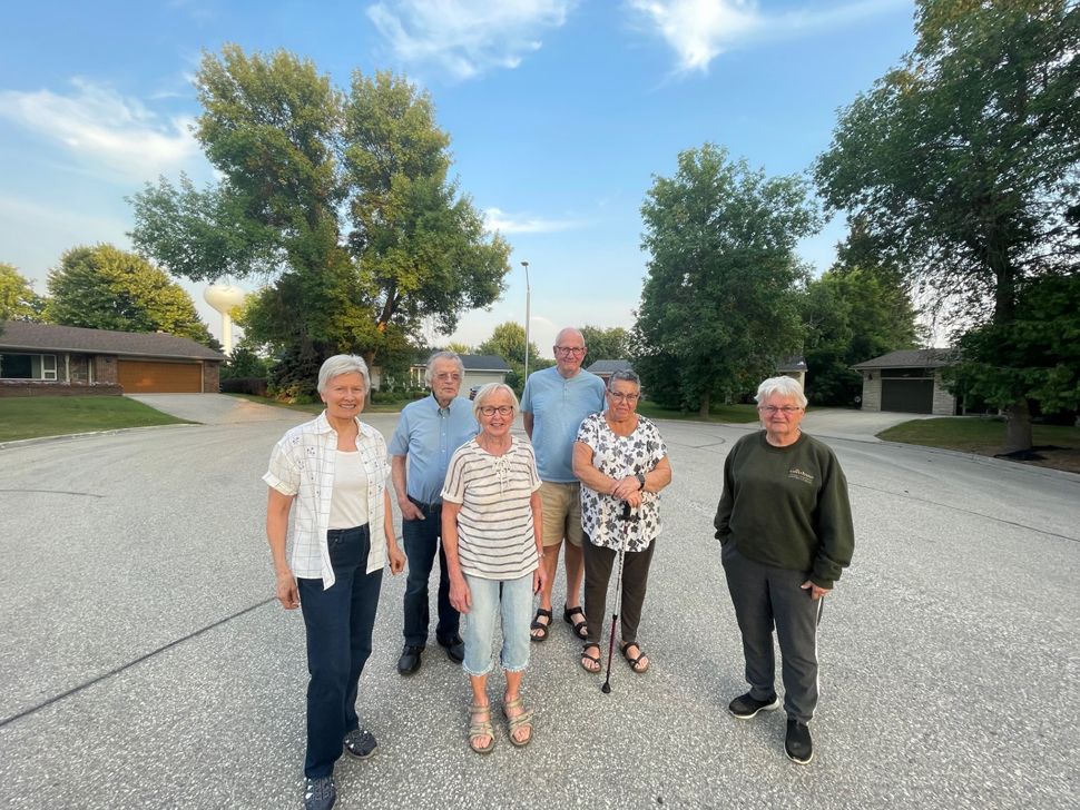 Four women and two men standing on the street at the end of a cul-de-sac with four houses behind them.