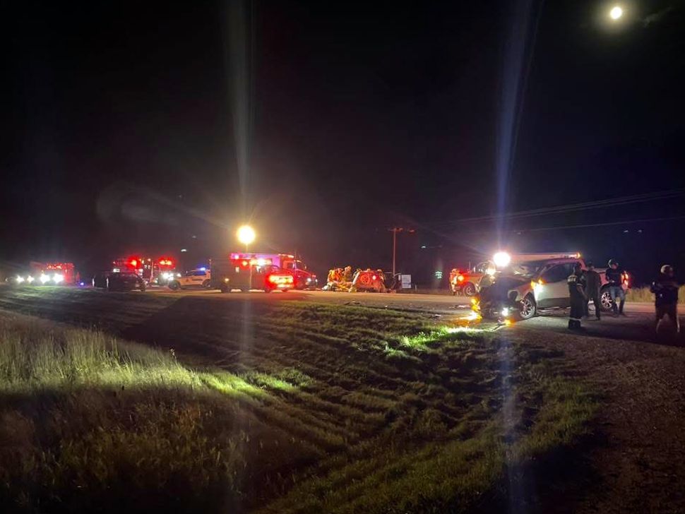 In the distance, there are emergency vehicles, lights are bright. The sky is a dark night sky.