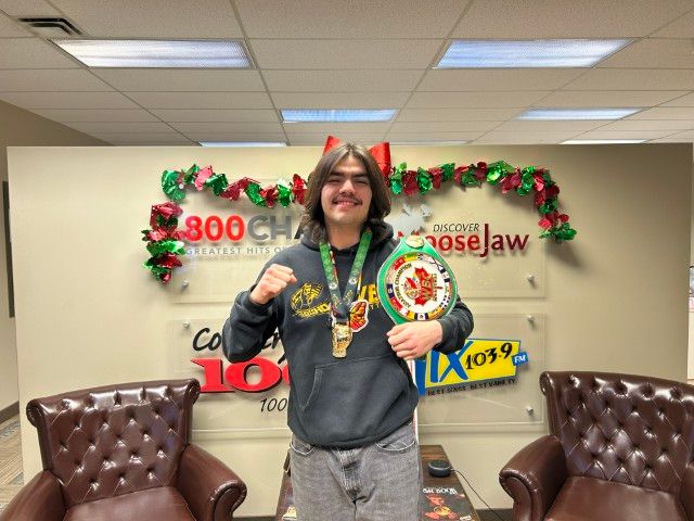 Cameron Billy in studio with his championship hard wear inside the Discover Moose Jaw office.