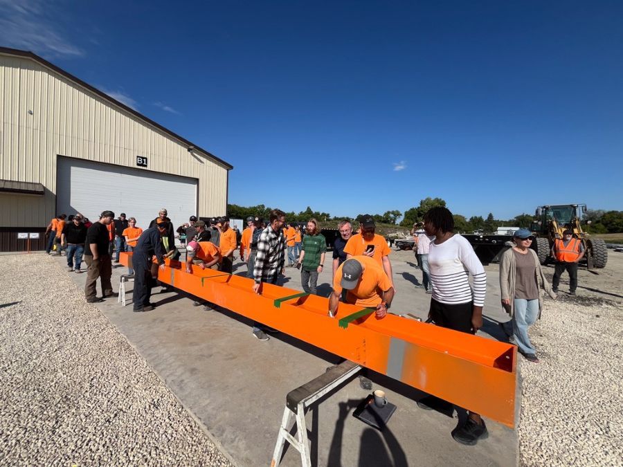 people signing a large metal beam