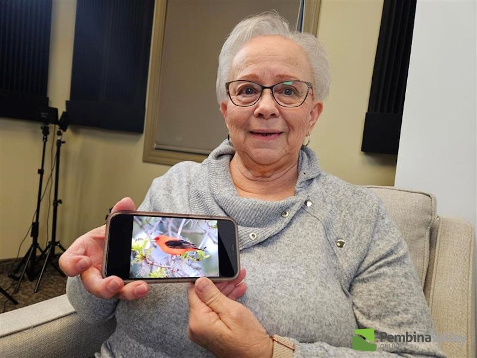 A woman showcases a phone with an image of an orange bird on it