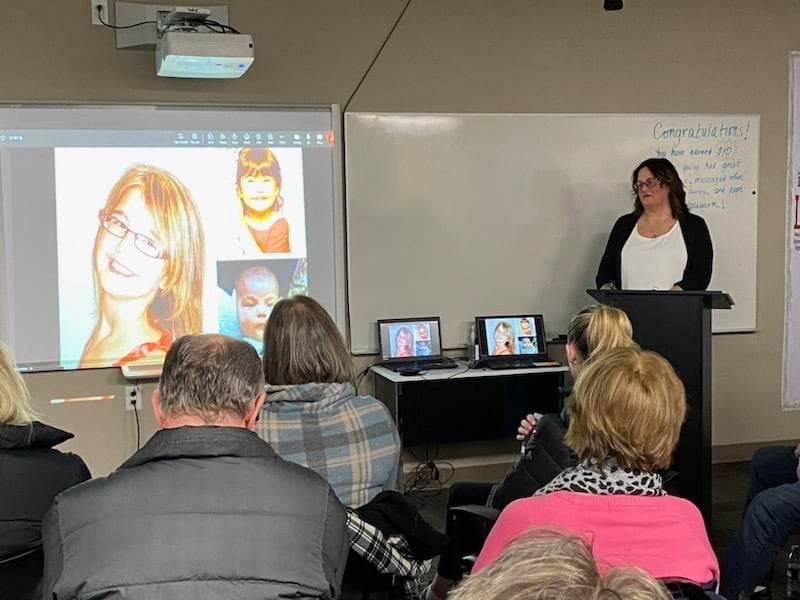 Woman with photo of her daughter on a projector screen speaking in front of a group