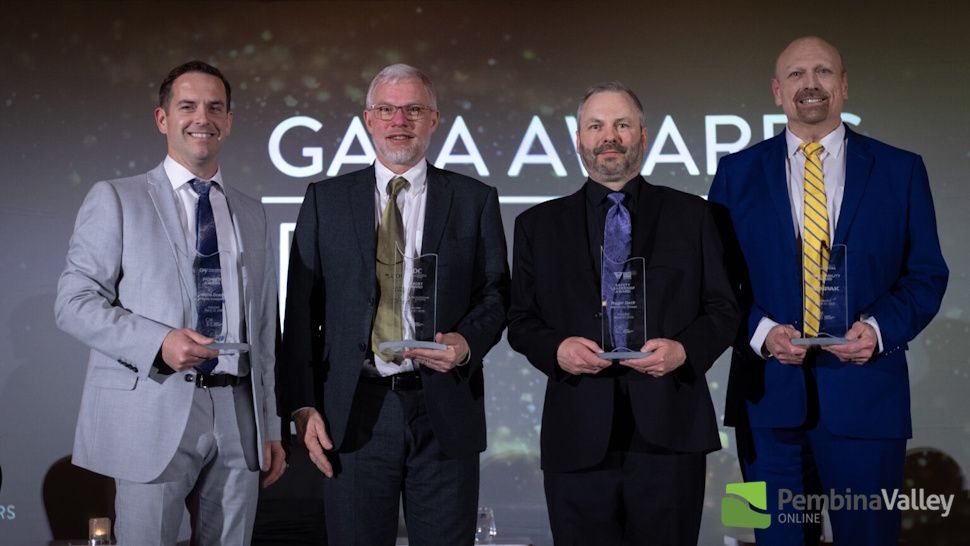 four men stand with awards