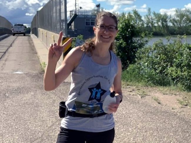 Diane Wing runs outdoors on a sunny day, smiling at the camera as she takes on a training run in preparation for her cross-Manitoba journey.