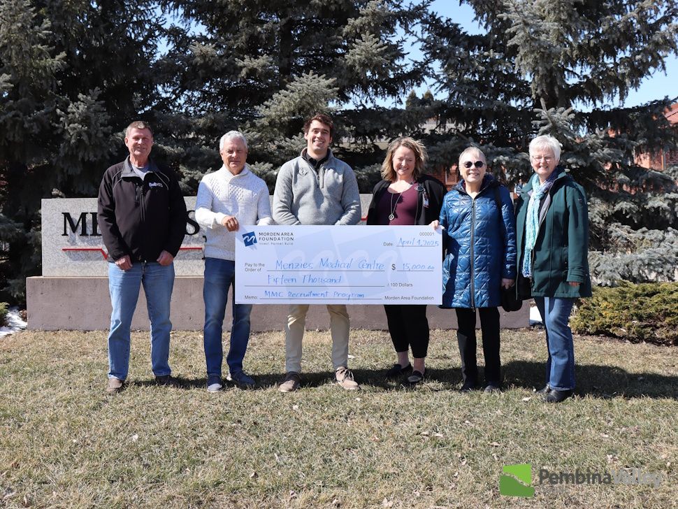 a group of people stand behind a giant cheque